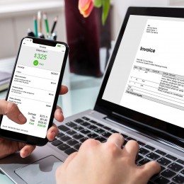 mobile phone paying an invoice shown on the laptop