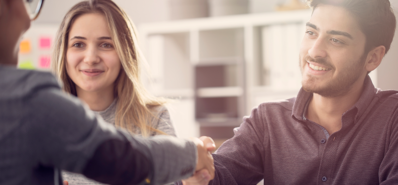 young couple shaking hands with a banker