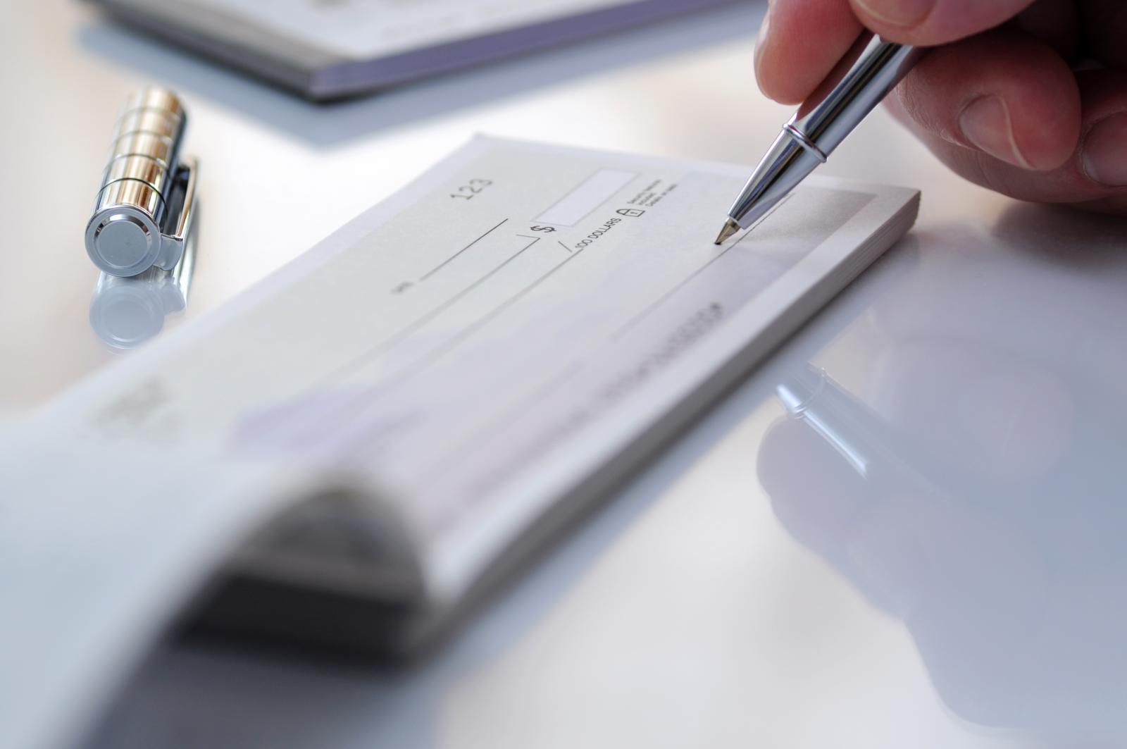 a hand signing a check with a pen