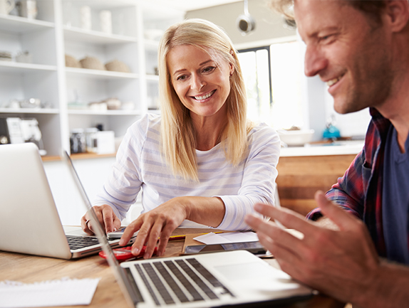 young couple sitting at home looking at computers